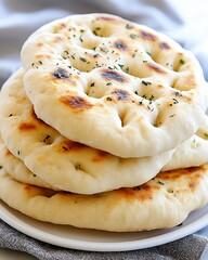 Closeup of Four Golden Brown Flatbreads with Herbs on White Plate