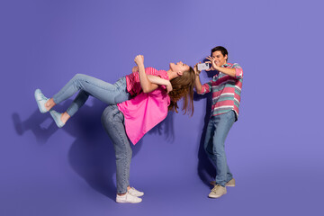 Obraz premium Two young friends enjoying a playful moment against a vibrant violet background showcasing positive energy