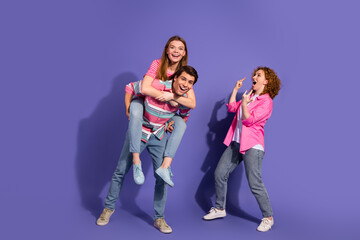 Fototapeta premium Dynamic group of young friends enjoying playful moments together against a purple backdrop showcasing fun, diversity
