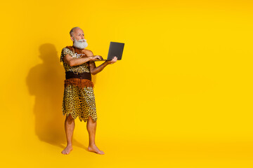 Full body portrait of aged primeval caveman use laptop empty space wear leopard skin clothes...
