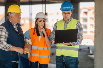Engineers using laptop discussing project at construction site