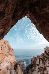 Ocean view framed by rocky cave opening with dramatic sky and seascape