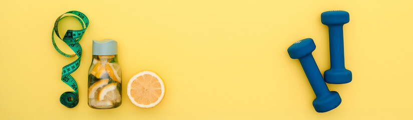 orange, sleek water bottle, tape measure, and dumbbells set against a bright yellow backdrop, forming a dynamic composition that highlights the essentials for an active and health-focused routine