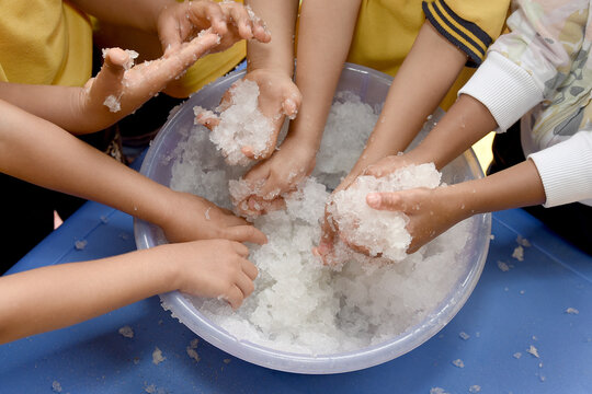 Infant sensory stimulation therapy: Several children place their hands in a plastic container containing sodium polyacrylate polymer to develop cognitive and psychomotor skills.