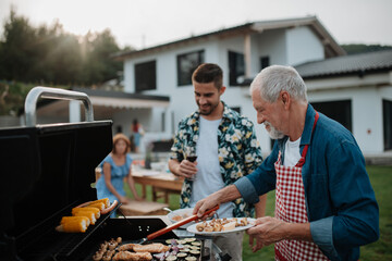Father-in-law and son-in-law preparing food for a family barbecue.