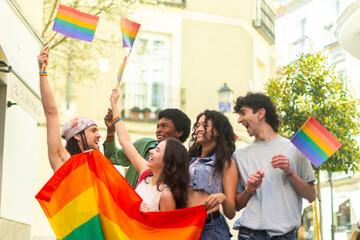 Young activists waving rainbow flags at pride parade celebrating lgbtq plus community