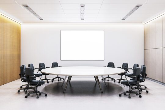 Modern corporate meeting room with round table, office chairs, and blank poster frame on wall in clean interior with wood and concrete panels. 3D Rendering