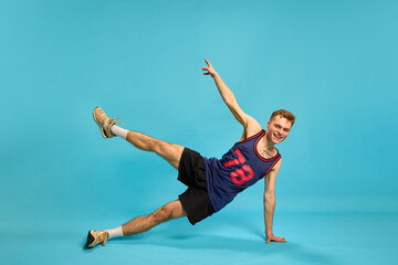 Young man balancing on one hand with lifted leg, smiling and focused, showing control, strength and...