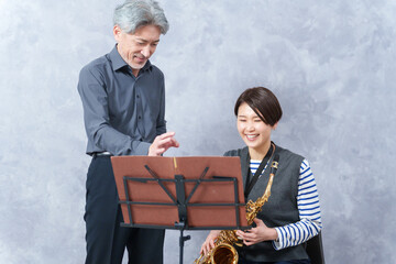 レッスンする大人の音楽教室の先生とサックスを教わる生徒