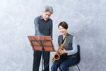 レッスンする大人の音楽教室の先生とサックスを教わる生徒