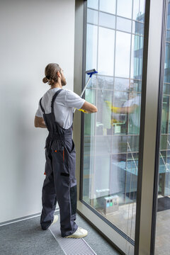 Young man cleaning the window with the window washer