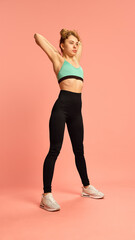 Fototapeta premium Sporty woman in mint top stretching triceps over head, preparing body for workout session, promoting muscle readiness and upper body focus. Concept of sport, wellness, activity.