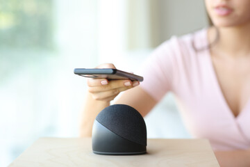 Woman hand pairing cell phone with smart speaker