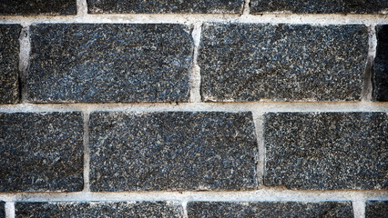 Wall of stones. Brick wall. Gray background with black geometric patterns, of rectangular stones, bricks. Part of a stone wall pattern for background, texture or text. rough grainy stone wall