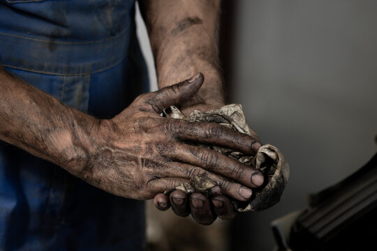 Close-up of dirty male hands. A man wipes his hands on a rag after working in the garage.