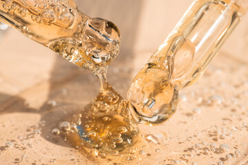 Liquid texture of cosmetic gel, essential oil in pipettes on a beige background.