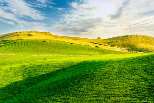 scenery rural view of a contryside farm in green fields and hills with amazing cloudy sky on background - Powered by Adobe