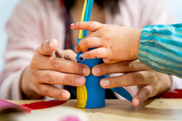 Close up of hands of Mother painting cardboard tube at home. Concept of recycling with creativity