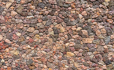colored unprocessed rocky stones of natural origin, a wall of stones in concrete, background for...