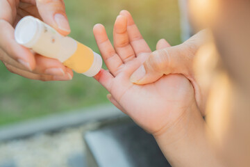 Mother hand applies healing ointment to a small wound on her son's hand.