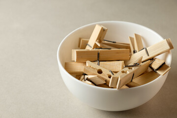 Delicate wooden clothespins gathered in a serene white bowl on a neutral surface