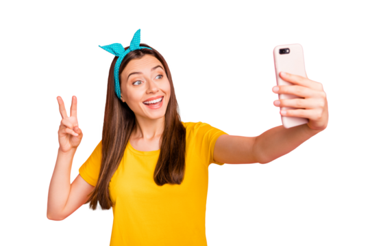 Portrait of amazed girl making photo v-signs smiling wearing yellow t-shirt isolated over pink background