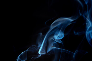 Wispy blue smoke wave flowing against a black background, creating a sense of mystery and elegance....