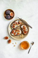 Figs and cheese toasts on the plate with jar of honey, top view