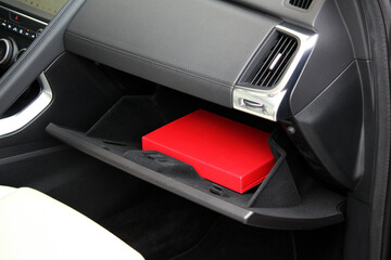 Open glove box with red folder in new car. Modern passenger airbag of car. Glove box in white car...