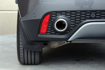 Close up of a silver exhaust pipe of new car. Close up of car exhaust pipe in new car bumper.