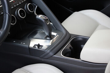 Close up automatic transmission shift selector in leather car interior. Car gear stick on parking...