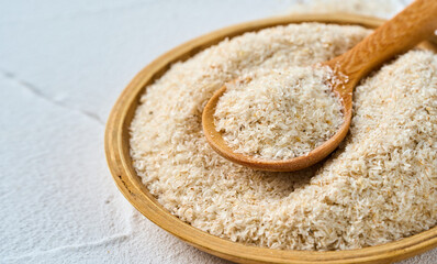 closeup psyllium husk in wood bowl and spoon on white table background with copy space