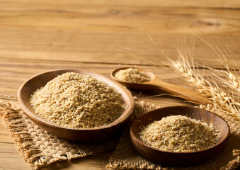 pile of flake whole grain powder or wheat germ in wood bowl and spoon on wooden table rustic style background with copy space
