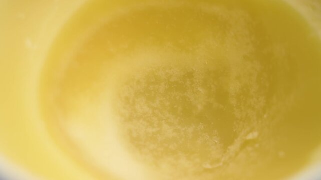 Clarified butter ghee in white ceramic container. Indian traditional dairy product. Macro shot. Rotation