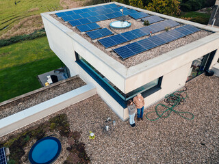 Grandfather and granddaughter on a rooftop with solar panels promoting sustainable energy