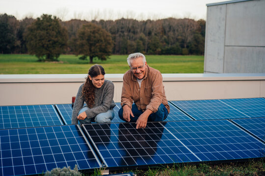 Grandfather and granddaughter bonding over solar panels outdoors