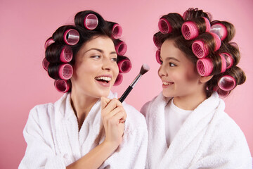 Attractive mother and daughter with hair curlers