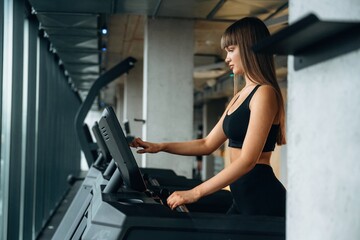 Fototapeta premium Using modern equipment, cardio concept. Young woman is in the gym