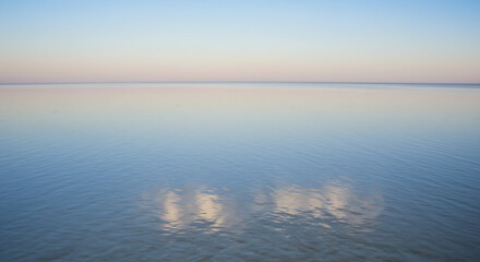 Obraz premium A smooth, still water surface under a soft gradient sky, creating a peaceful view.