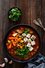 Fresh vegetable soup with chickpeas, feta cheese and cilantro on wooden table