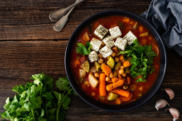 Fresh vegetable soup with chickpeas, feta cheese and cilantro on wooden table
