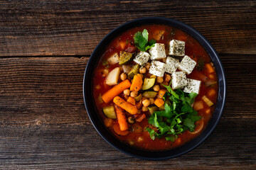 Fresh vegetable soup with chickpeas, feta cheese and cilantro on wooden table