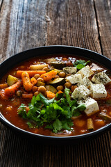 Fresh vegetable soup with chickpeas, feta cheese and cilantro on wooden table
