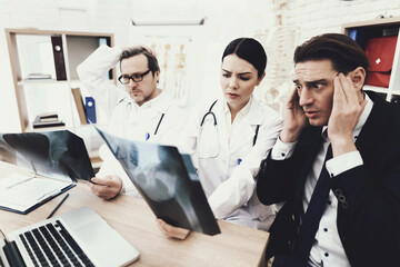 Fototapeta premium Adult businessman is horrified by diagnosis of doctor who keeps radiograph in medical office.