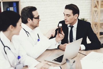 Obraz premium Experienced physician prescribes medicine for coughing to businessman in medical office.