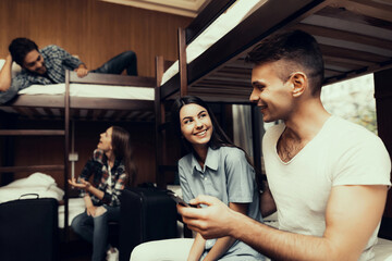 Girl and Man sit on beds and look at phone