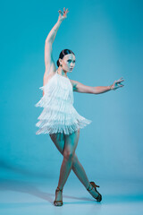 Naklejka premium Elegant dancer in fringed dress dancing solo salsa dance showing dramatic pose under artistic lighting