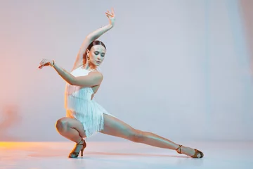 Dynamic dance solo. Woman dancing bachata on gradient yellow-orange background in neon light. Dance concept, lessons, school