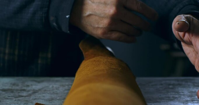 Super Slow Motion Macro of Artisan Unrolling Premium Leather Hide on Workbench in Workshop Beginning the Process of Handcrafted Leather Working with Traditional Materials and Skilled Hands at 1000 fps