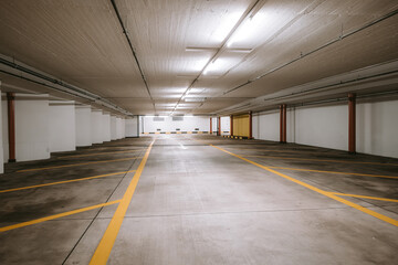 Empty, illuminated underground car parking lot. Wide angle view, no people, no cars